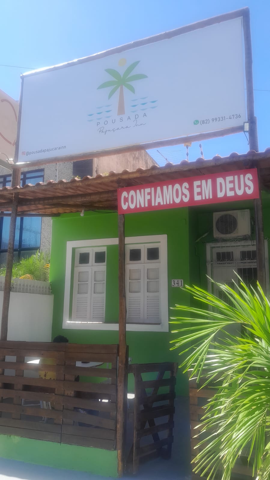 Fachada verde da Pousada Pajuçara Inn com placa da pousada